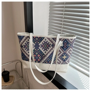 Detail of geometric pattern tote bag with white leather trim and long shoulder strap