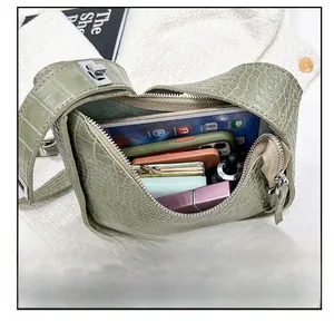 Internal capacity of green crocodile pattern crescent bag showing storage for daily items
