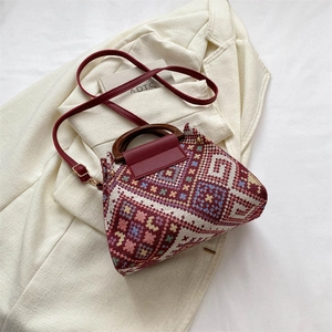 Nahaufnahme der gewebten Beuteltasche mit Lederklappe und rundem Holzgriff im Retro-Stil