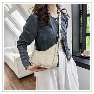 Detail shot of the cream crescent bag featuring premium crocodile pattern texture and strap