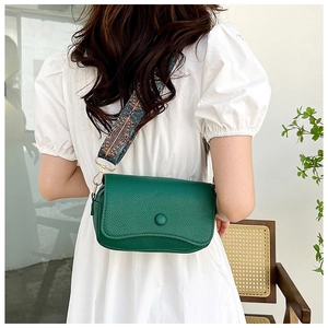 Green leather crossbody bag with ethnic embroidered strap shown on white dress