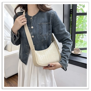 Chic cream crocodile pattern half-moon bag worn by model in a bright indoor setting