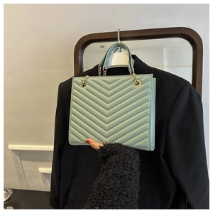 Detail of mint green quilted PU leather bag with elegant gold chain and V-pattern texture