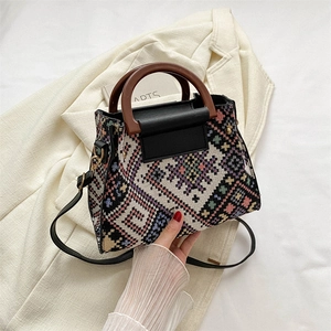 Ethnische Strick-Beuteltasche mit Holzgriff und Lederbesatz auf elegantem Blazer