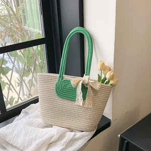 Minimalist beige woven tote bag with green handles and delicate lace bow decoration
