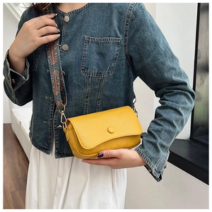Yellow pebble leather crossbody bag with ethnic embroidered wide strap worn by a model