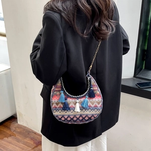 Detailed view of bohemian woven crescent bag with colorful tassels and golden chain