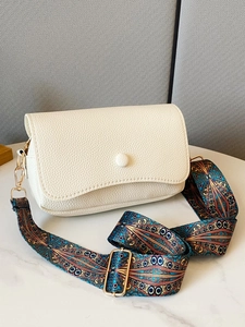 Detailed macro of white litchi pattern leather bag with ethnic geometric woven strap