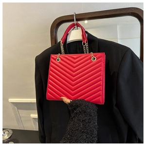 Detail of red quilted chevron shoulder bag with gold metal chain and leather strap