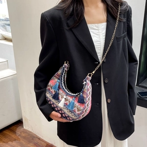 Close-up of bohemian crescent bag featuring colorful tassels and woven ethnic patterns