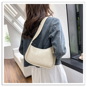 Detailed close-up of cream crocodile pattern hobo bag worn over the shoulder