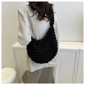 Detail of black popcorn textured cloud bag showing the unique bubble fabric on a model