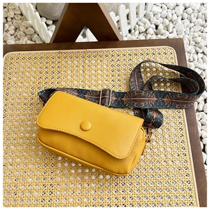 Detail of yellow lychee textured crossbody bag with ethnic style embroidered wide strap