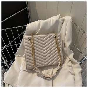 Detail of cream chevron quilted handbag featuring gold chain strap and elegant texture