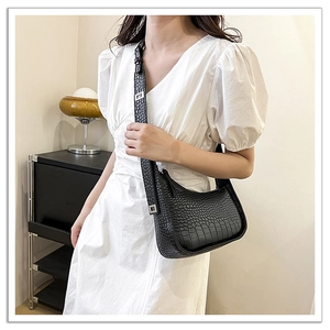 Detail view of black crocodile pattern hobo bag with adjustable silver buckle strap