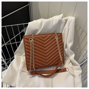 Detail of brown V-quilted faux leather bag with gold chain strap in a metal basket