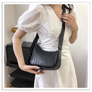 Detail of black faux leather crescent bag with crocodile texture on shoulder strap