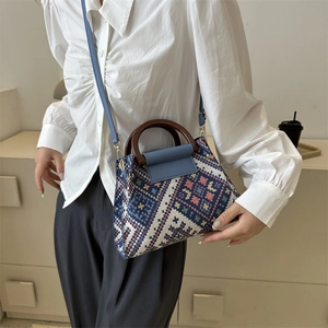 Detail der Retro-Web-Eimertasche mit Holzgriff und blauem Lederklappenverschluss