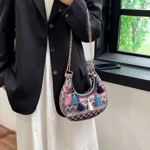 Close-up of Bohemian crescent bag with ethnic weaving patterns and blue fringe tassels