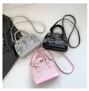 Detailed top view of embroidered shell-shaped handbags in grey, black, and pink with gold zippers