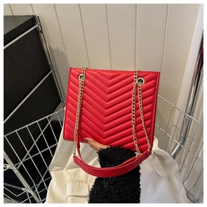 Close-up of red chevron quilted leather bag with elegant gold chain shoulder strap