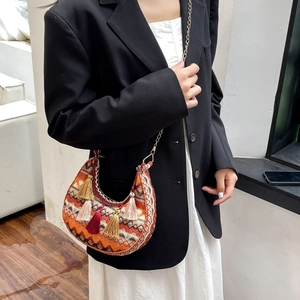 Detail of bohemian crescent bag with orange geometric patterns and colorful tassels