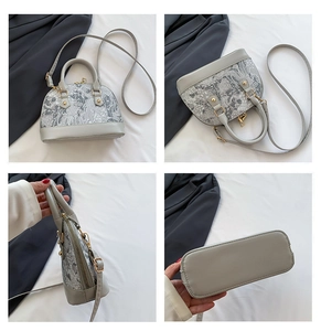 Detail view of grey shell bag showing embroidered fabric and rivet gold accents