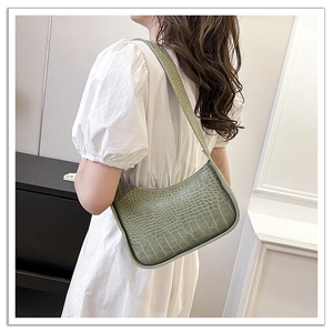 Detail of green crocodile pattern shoulder bag shown from a back perspective on a model
