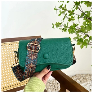 Detail of dark green lychee textured crossbody bag with colorful woven ethnic strap