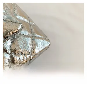 Détail de la texture en cuir synthétique argenté métallisé avec surpiqûres en losange