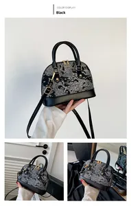 Detail of black shell bag with white floral embroidery and gold zipper hardware