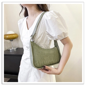 Detail of green crocodile texture on a crescent hobo shoulder bag with silver buckle