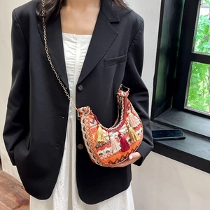 Detail of bohemian crescent bag featuring colorful tassels and woven ethnic patterns