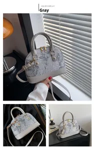 Close-up of the grey shell bag showing jacquard embroidery and gold hardware details
