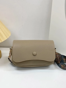 Detail of khaki pebbled leather crossbody bag with decorative floral silk scarf and gold buckle