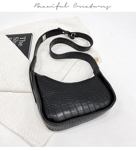 Detailed view of the crocodile embossed texture and metal buckle on this black hobo bag