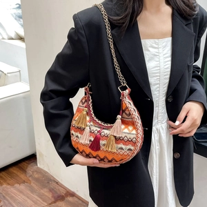 Detail of bohemian woven crescent bag with colorful tassels and gold metal chain strap