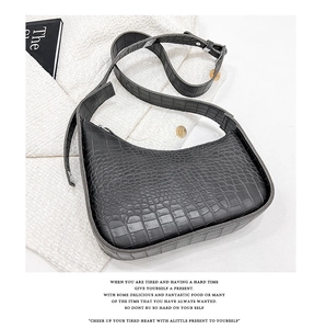 Detail of black crocodile pattern hobo bag with adjustable strap on tweed fabric