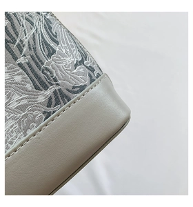 Detailed close-up of textured jacquard fabric and stitching on shell handbag