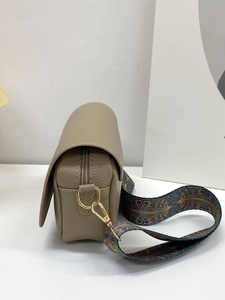 Detail view of khaki lychee grain leather crossbody bag with wide ethnic woven strap