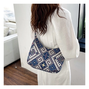 Gros plan d'un sac à main tissé à motifs géométriques porté par un mannequin dans un décor épuré