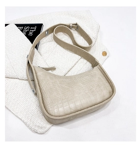 Detailed view of beige crocodile embossed leather on a crescent hobo shoulder bag
