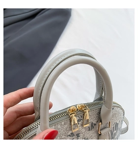 Detail of grey shell handbag featuring jacquard fabric and double gold metal zippers