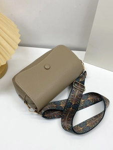 Close-up of khaki pebbled leather crossbody bag with ethnic style woven wide strap
