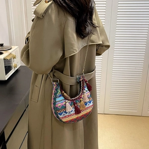 Close-up of bohemian crescent bag with colorful tassels and golden chain strap on shoulder