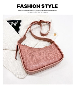 Detail of dusty rose crescent bag with crocodile texture on white tweed coat