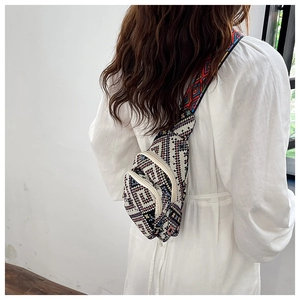 Detailed back view of a colorful ethnic woven chest bag with adjustable wide strap on model