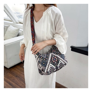 Gros plan d'un sac ethnique en tricot avec motifs géométriques colorés sur robe blanche