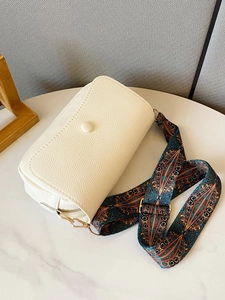 Detail of off-white lychee texture leather bag with colorful ethnic pattern wide strap