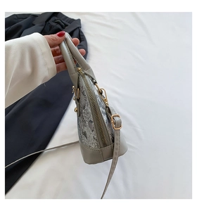 Detail showing grey shell bag with lace side panels and gold metal zipper hardware